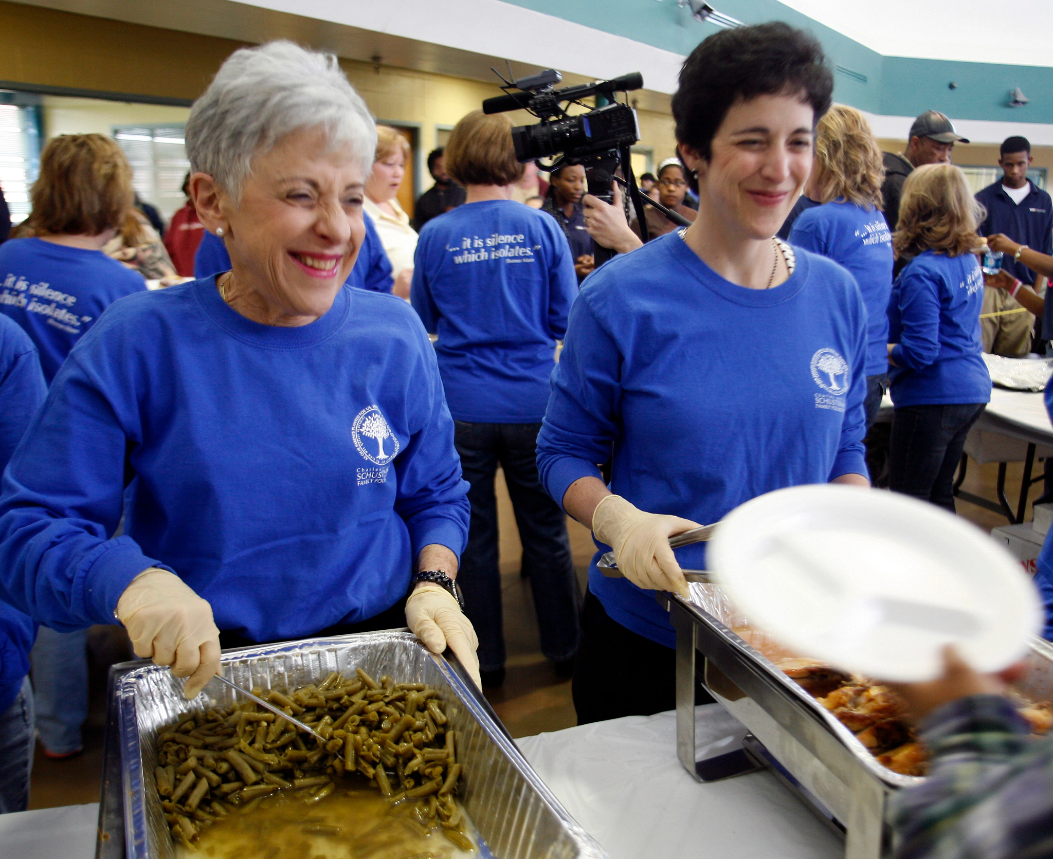 Lynn and Stacy Schusterman wearing t-shirts, serving hot food to crowd