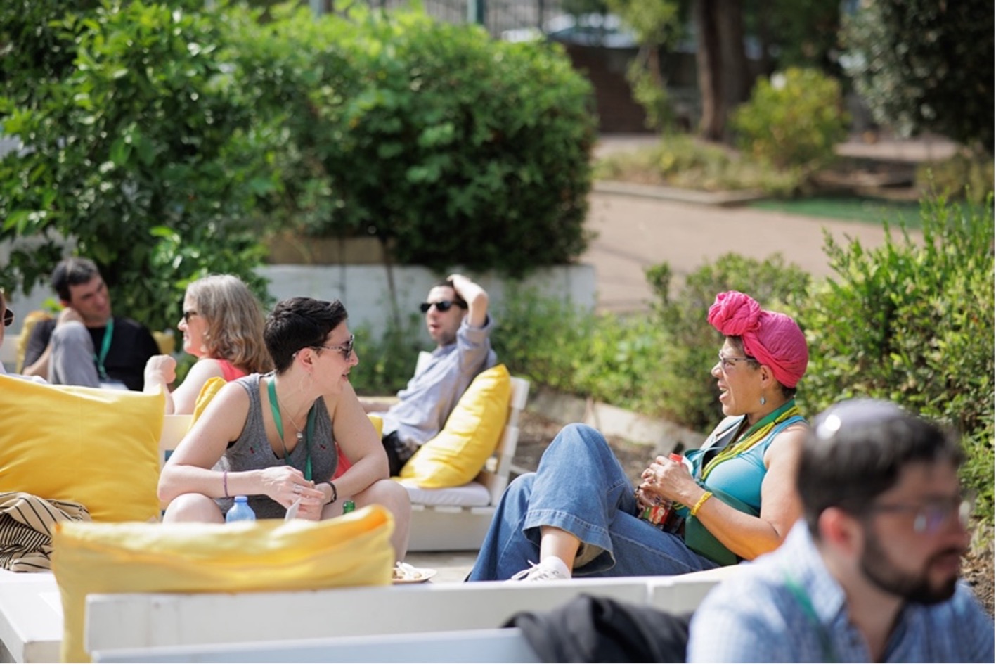 Five adults sit outside relaxing in a professional setting while engaged in various conversations.