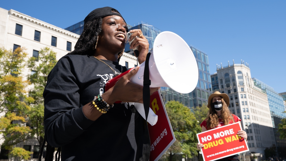 Women on sidewalk holding signs: No More Drug War